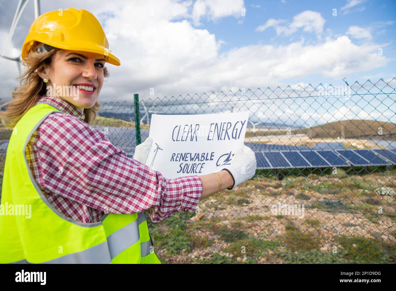 Eine Ingenieurin in einem Solarkraftwerk mit einem Blatt mit der Aufschrift „Clean Energy Renewable source“ Stockfoto