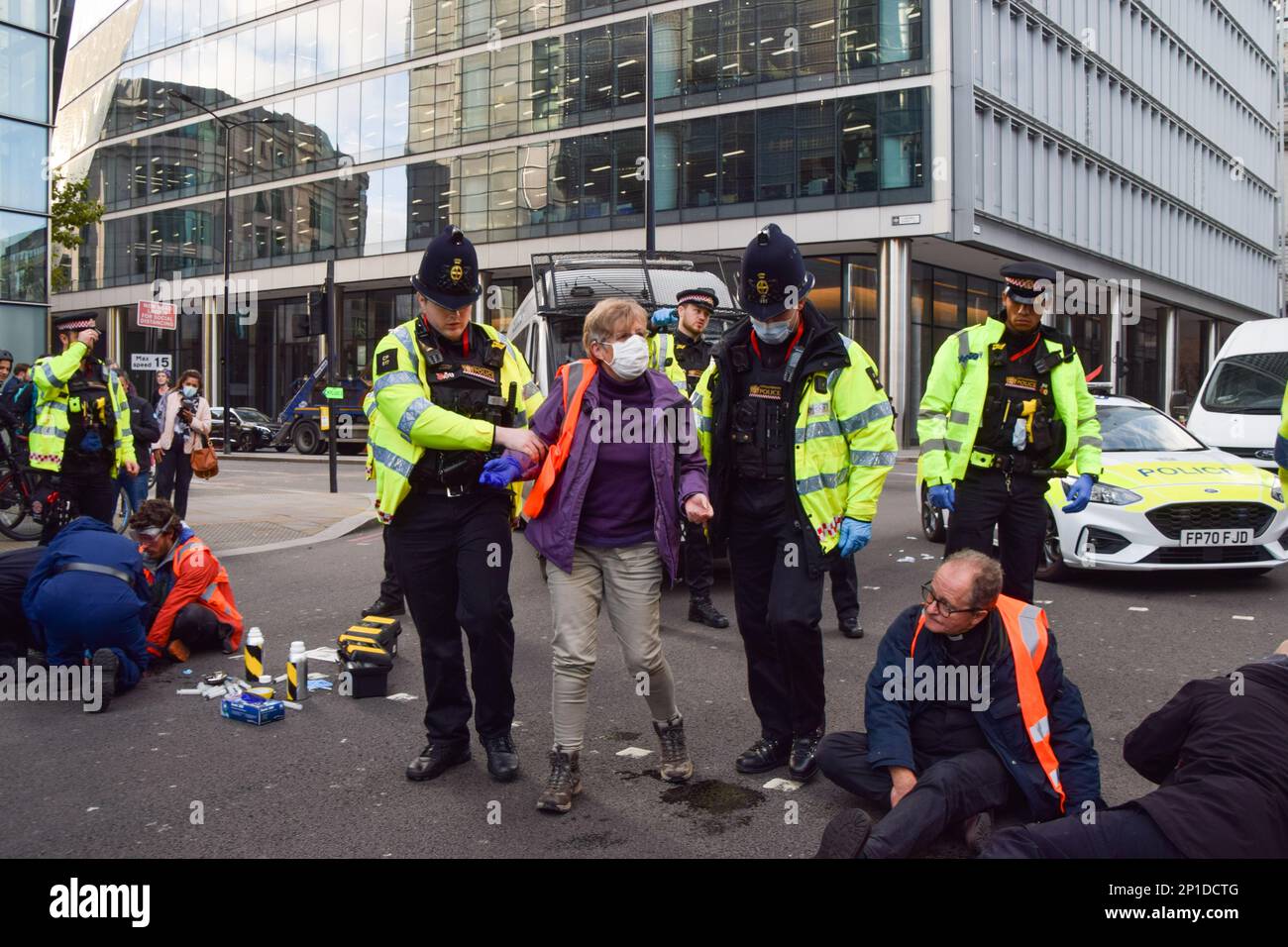 London, Großbritannien. 25. Oktober 2021. Die Polizei verhaftet einen Priesterprotestierenden. Isolierte britische Demonstranten klebten sich an die Straße und blockierten die Wormwood Street und Bishopsgate, nahe der Liverpool Street Station. Stockfoto