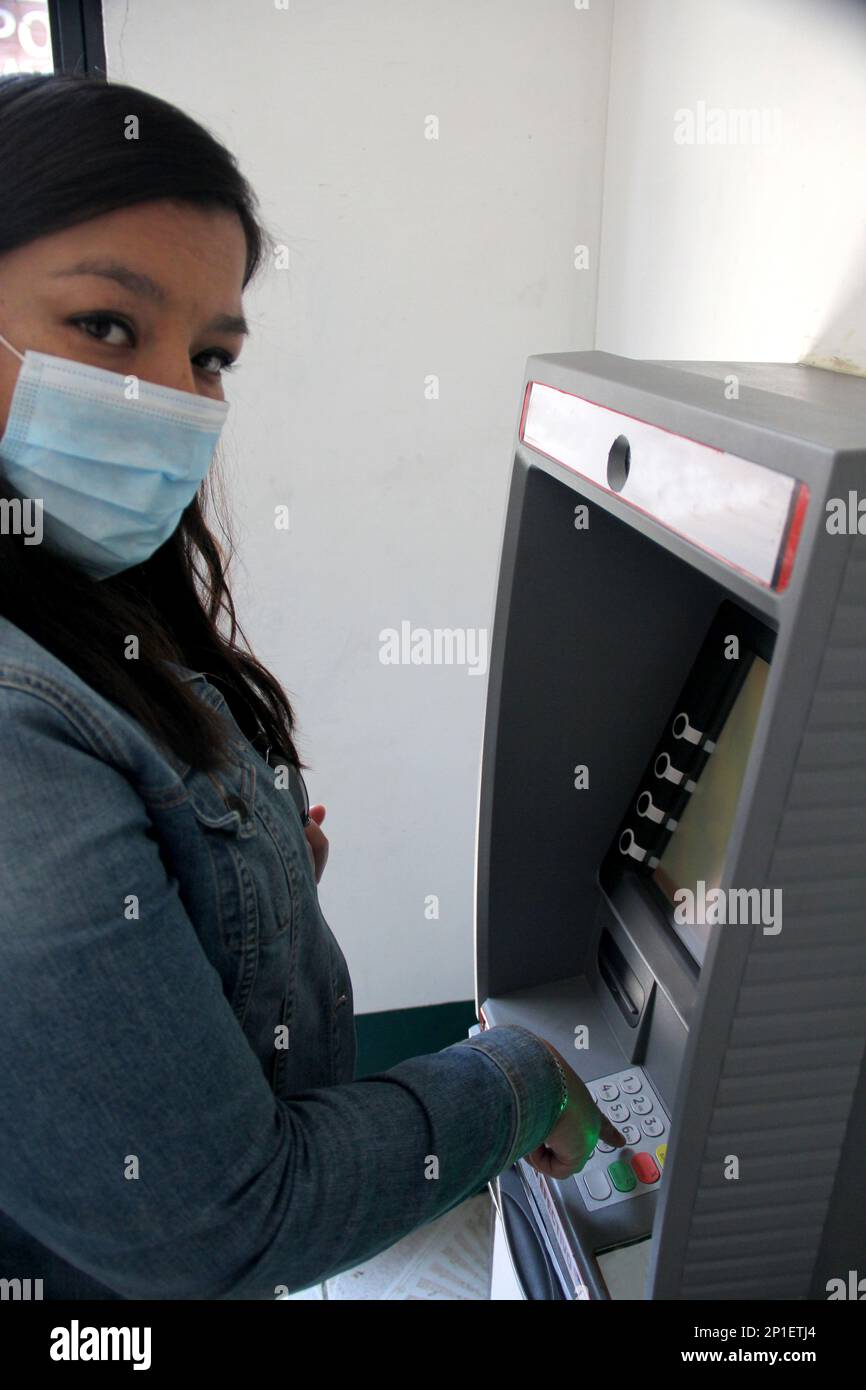 Lateinische Frau mit Schutzmaske klinische Anwendung im Geldautomaten Geld von der Bank abheben, neue normal Stockfoto