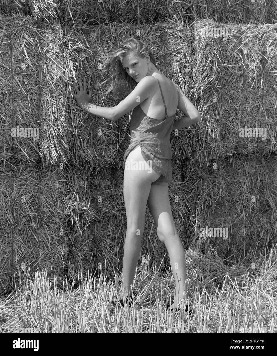 Junge, hübsche, blonde Frau in Unterwäsche, die für ein Porträt posiert, im Heuballen-Stack Landside 1990er england uk Stockfoto
