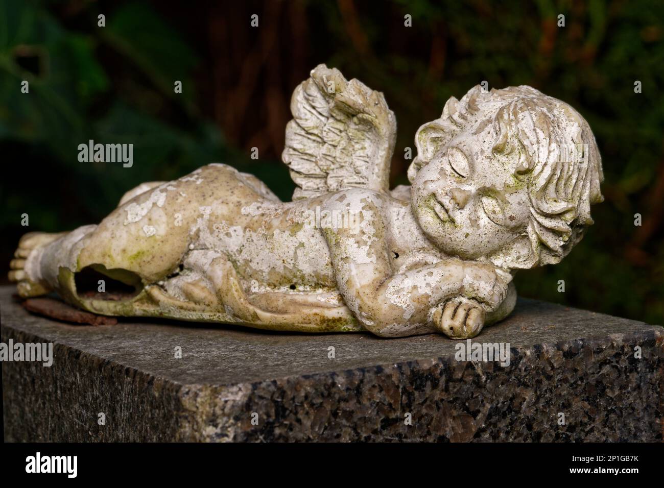 Beschädigter und verwitterter kleiner geflügelter Engel liegt auf Grabstein Stockfoto