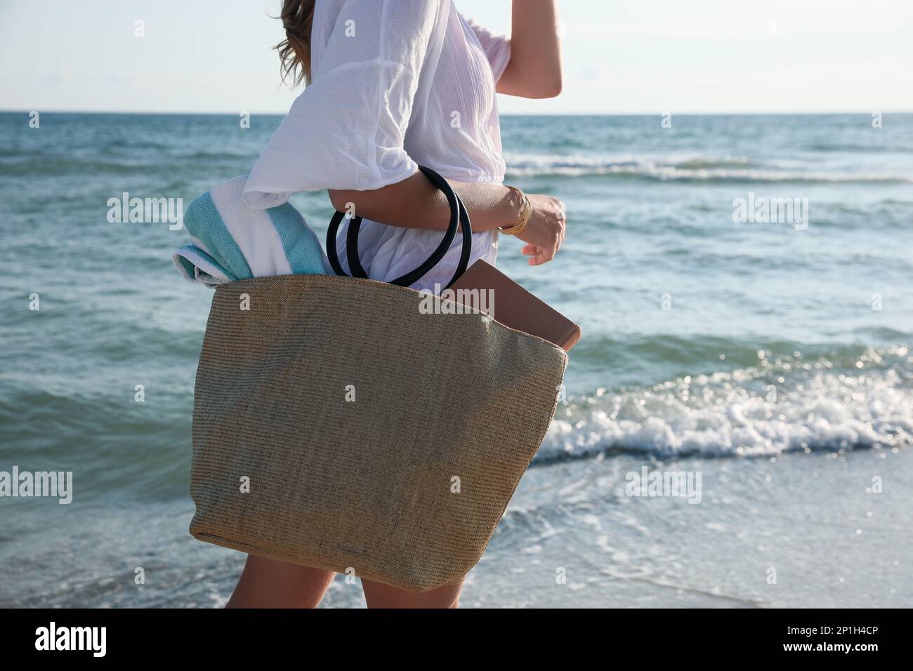 Eine Frau, die eine Tasche mit Strandtuch in der Nähe des Meeres trägt,  Nahaufnahme Stockfotografie - Alamy