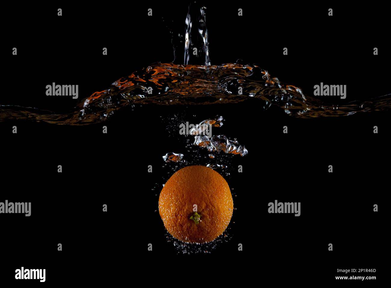 Orangefarbener Wasserstrahl auf schwarzem Hintergrund zeigt den Wasserstand an. Stockfoto