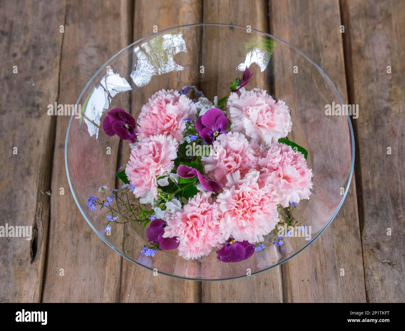 Glasschale mit Blumen auf dem Gartentisch Stockfoto
