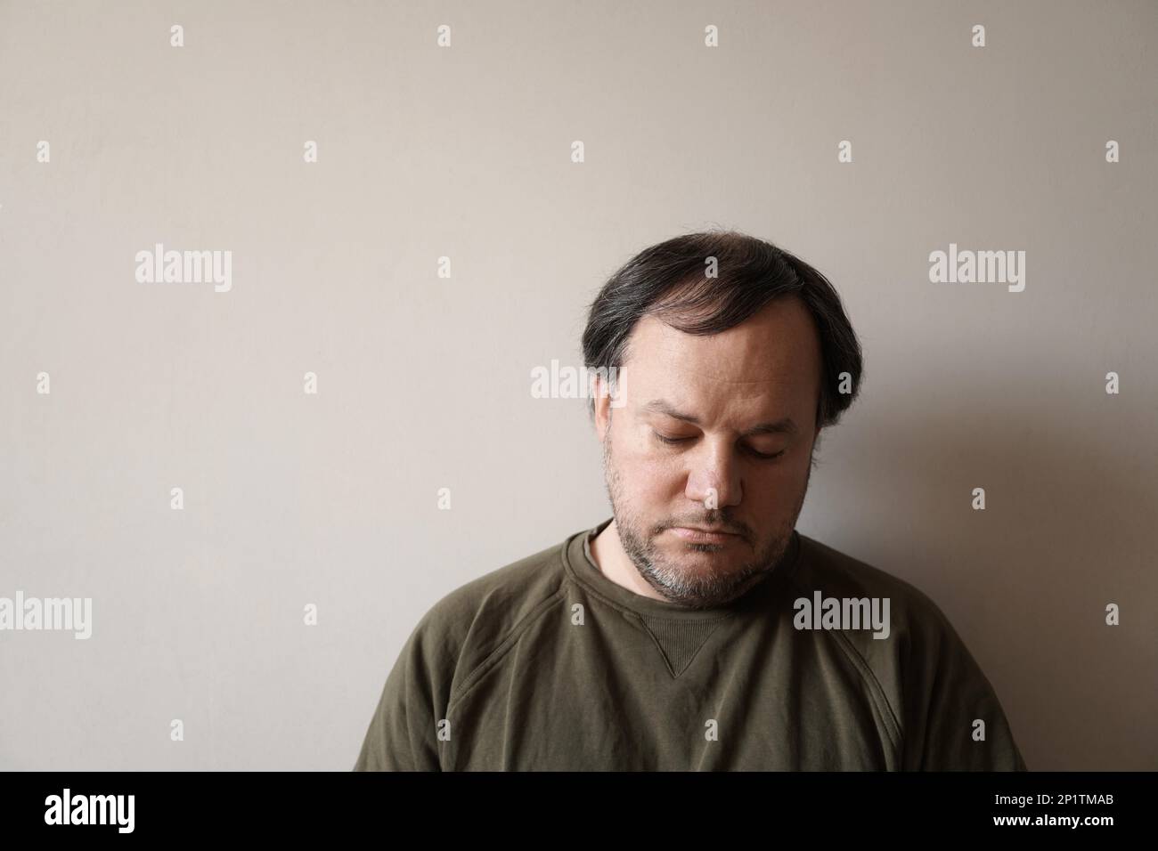 Ein depressiver Mann in den Vierzigern lehnt sich mit Kopierraum an die Wand. Depression oder Midlife-Crisis-Konzept Stockfoto
