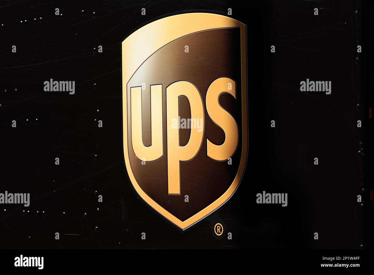 United Postal Service, UPS Markenlogo in goldenen Buchstaben auf braunem Lieferwagen Stockfoto