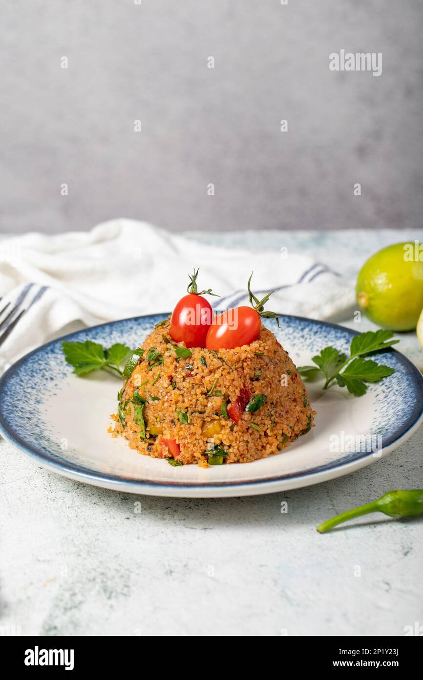 Bulgur-Salat auf grauem Hintergrund. Traditioneller türkischer bulgarischer Salat oder kısır salatası Stockfoto