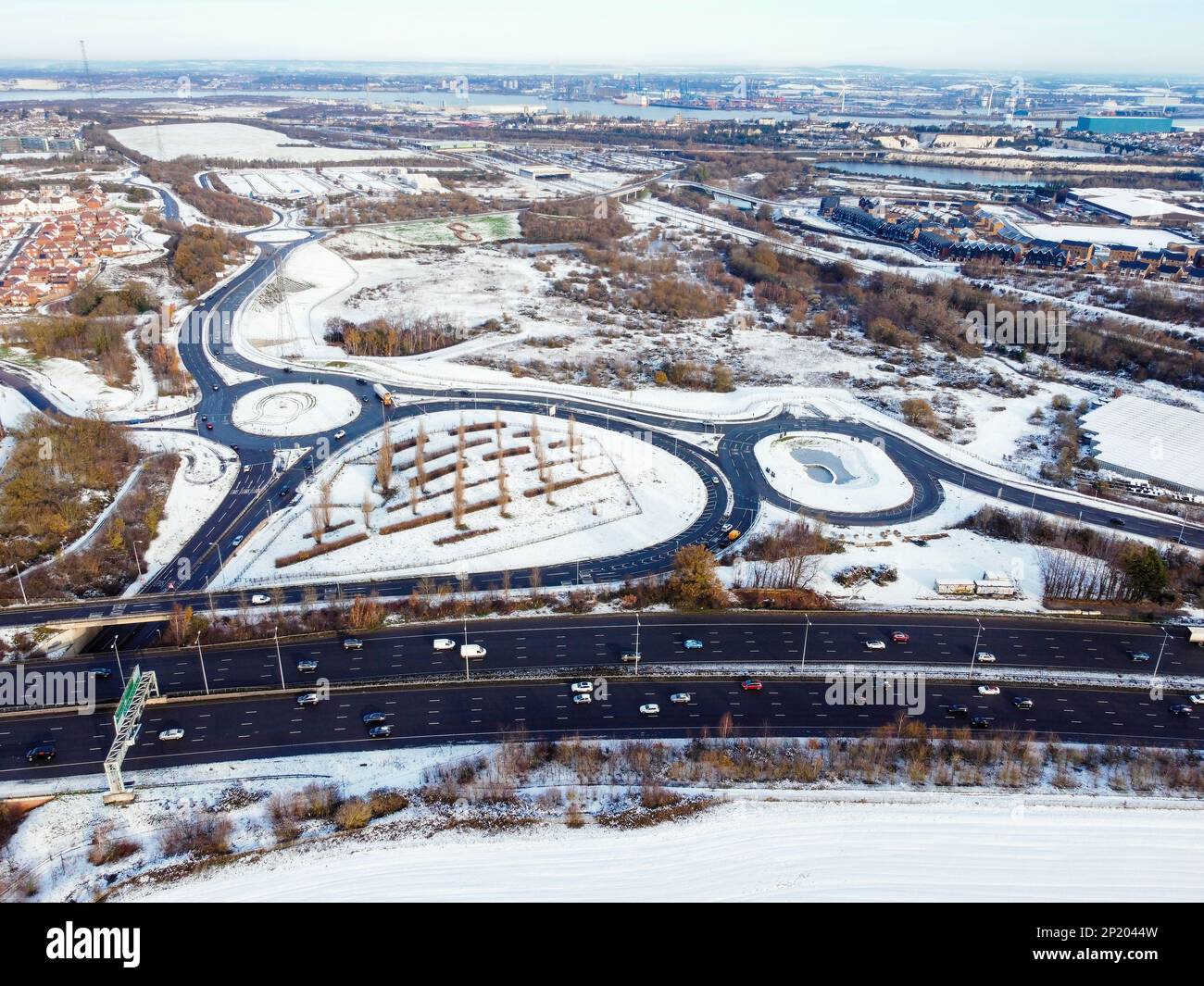 Luftdrohne. Ebbsfleet Garden City in Kent, im Dezember 2022 von Schnee bedeckt. Neubauten und gefrorener See entlang der Autobahn A2. Stockfoto