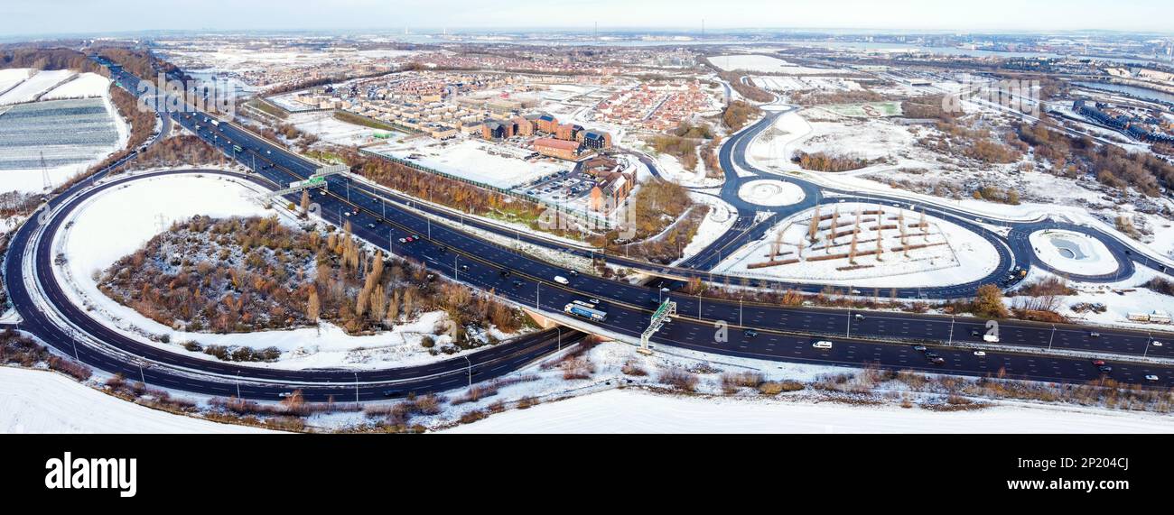 Luftdrohne. Ebbsfleet Garden City in Kent, im Dezember 2022 von Schnee bedeckt. Neubauten und gefrorener See entlang der Autobahn A2. Stockfoto