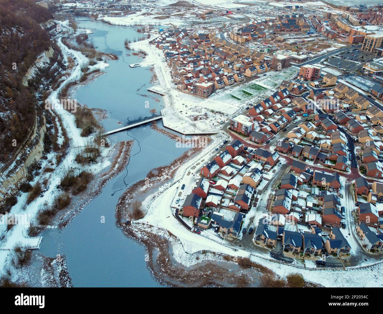 Luftdrohne. Ebbsfleet Garden City in Kent, im Dezember 2022 von Schnee bedeckt. Neubauten und gefrorener See entlang der Autobahn A2. Stockfoto