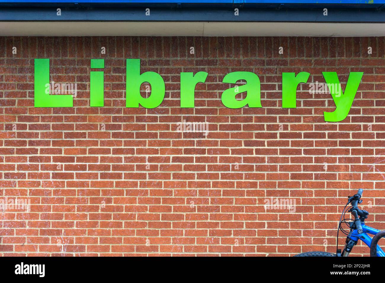 Das Wort Bibliothek in großen grünen Buchstaben auf der Ziegelwand einer öffentlichen Bibliothek. Stockfoto