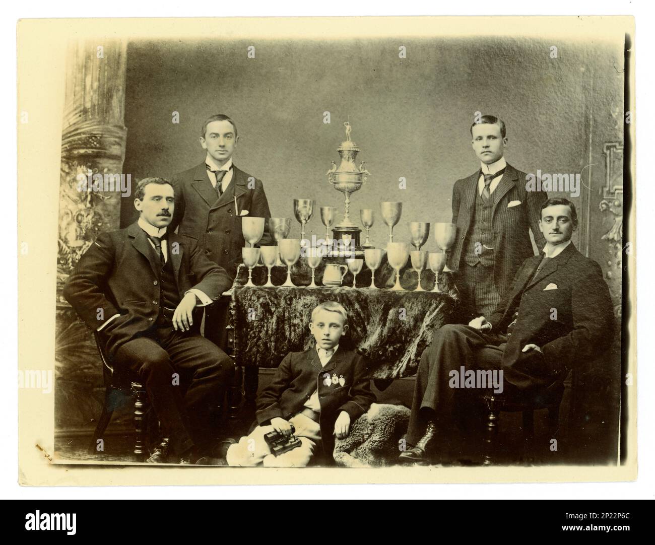 Original-viktorianisches Foto-Gruppenporträt von Herren und einem Kind. Auf einem Tisch befindet sich eine große Worcester Challenge Vase,/Regatta-Trophäe zum Rudern und andere Pokale, möglicherweise Mitglieder einer gefrästen vier-Mannschaft. Worcester und Umgebung, Großbritannien, ca. 1897-1899. Stockfoto