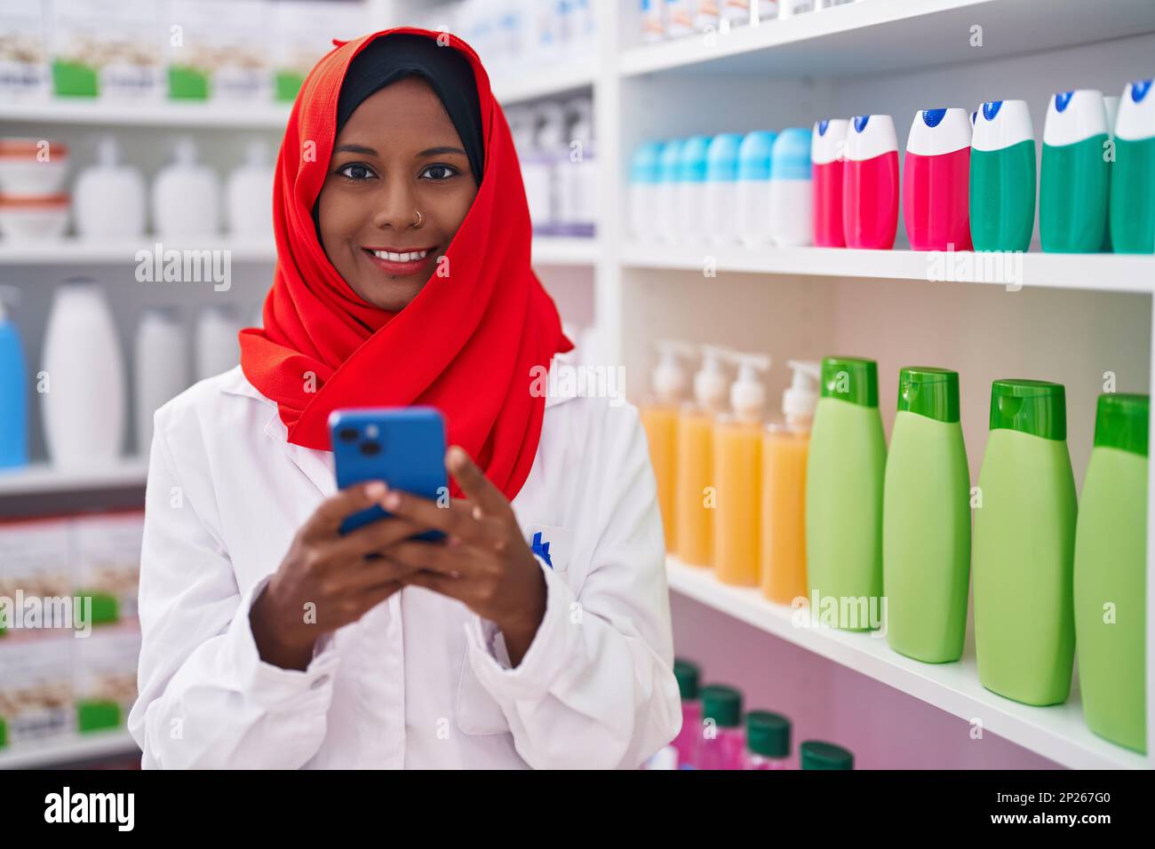 Junge, schöne Apothekerin mit Smartphone, die in der Apotheke arbeitet Stockfoto
