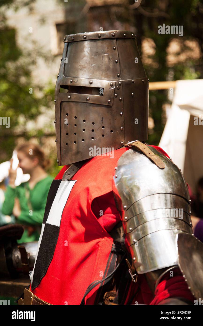 Mittelalter Kostümen am Ritterturnier. Mittelalterliche historisches Reenactment - ein Mann mit Metall großer Helm und rote Rüstung Anzug Stockfoto