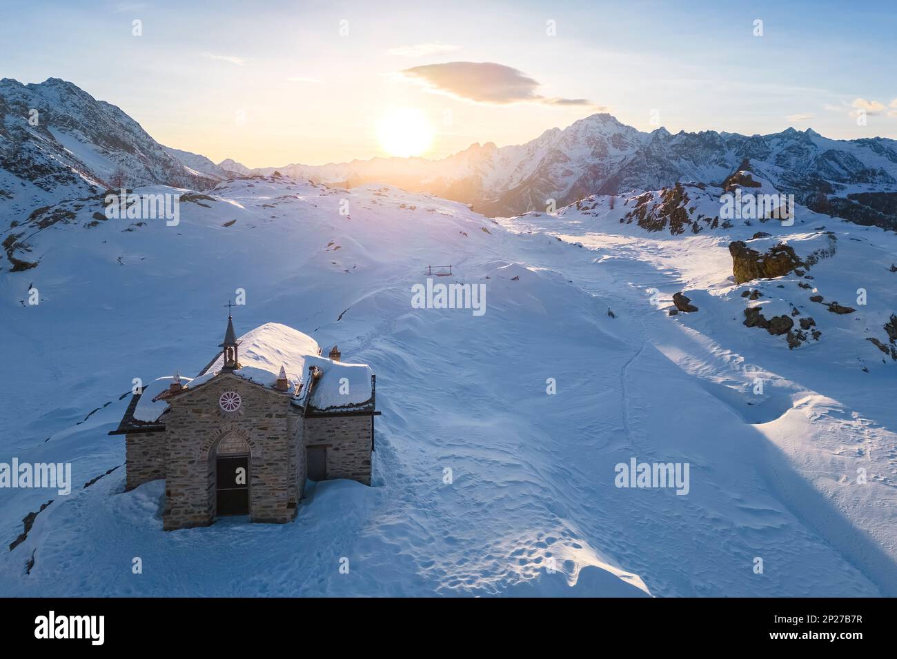 Sonnenuntergang am Alpe Prabello mit Santuario Madonna della Pace im Winter. Lanzada, Valmalenco, Valtellina, Sondrio District, Lombardei, Italien, Europa. Stockfoto