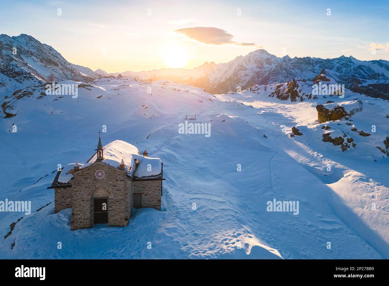 Sonnenuntergang am Alpe Prabello mit Santuario Madonna della Pace im Winter. Lanzada, Valmalenco, Valtellina, Sondrio District, Lombardei, Italien, Europa. Stockfoto