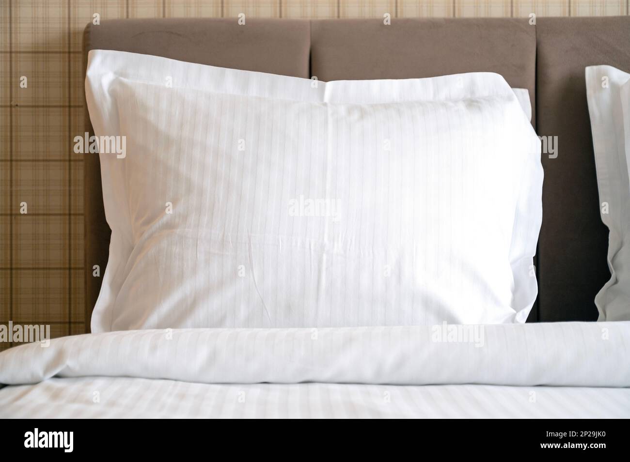 Nahaufnahme weißer Kissen auf einem Bett im Hotel, weißes, sauberes Kissen in einem komfortablen Zimmer, Blick nach vorne Stockfoto