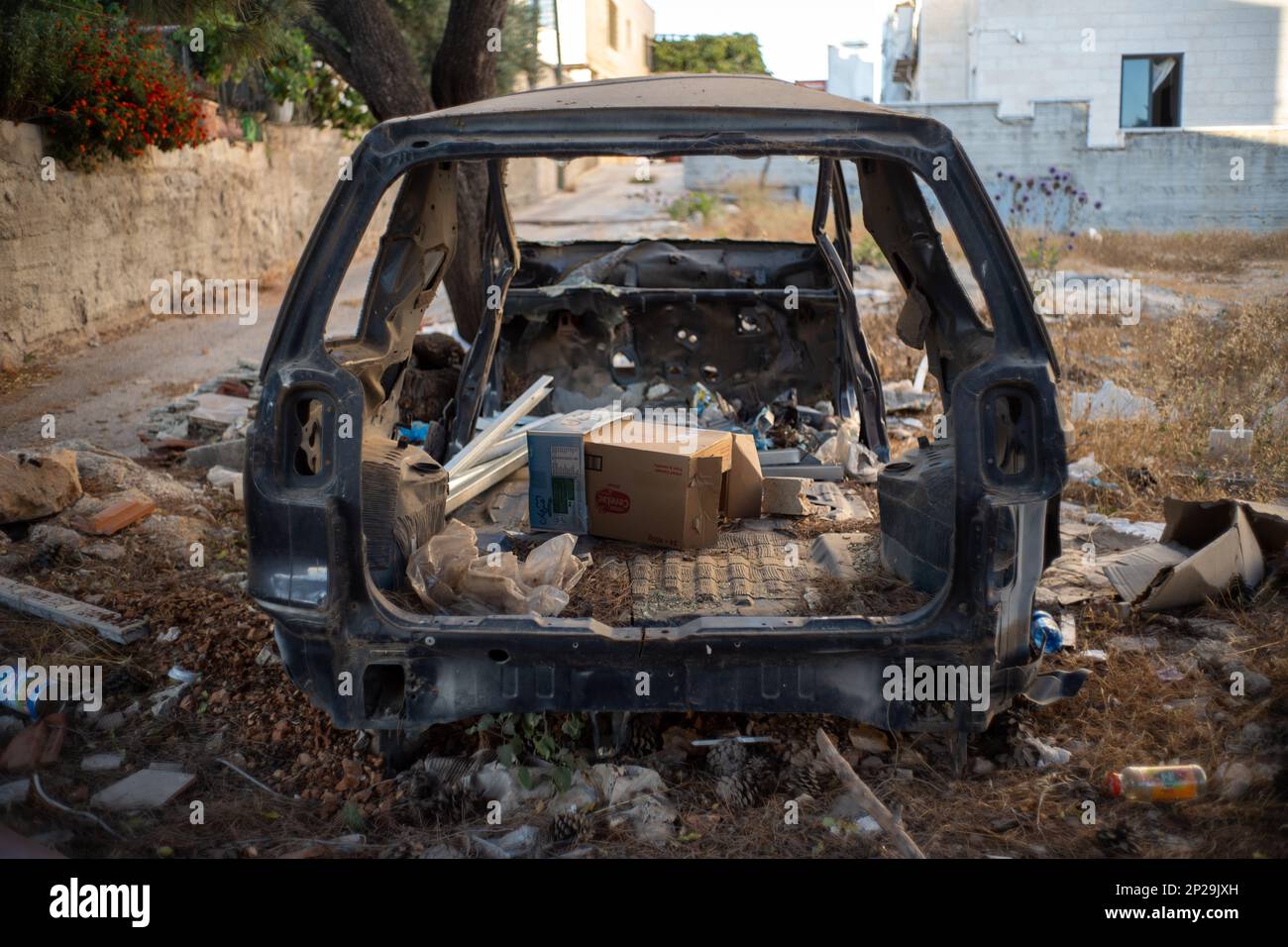 Ramallah, Ramallah und al-Bireh Governorate, Palästina, 20. Juli 2022: Altes zerstörtes Fahrzeug auf einer Straße voller Junk auf einem leeren Grundstück Stockfoto