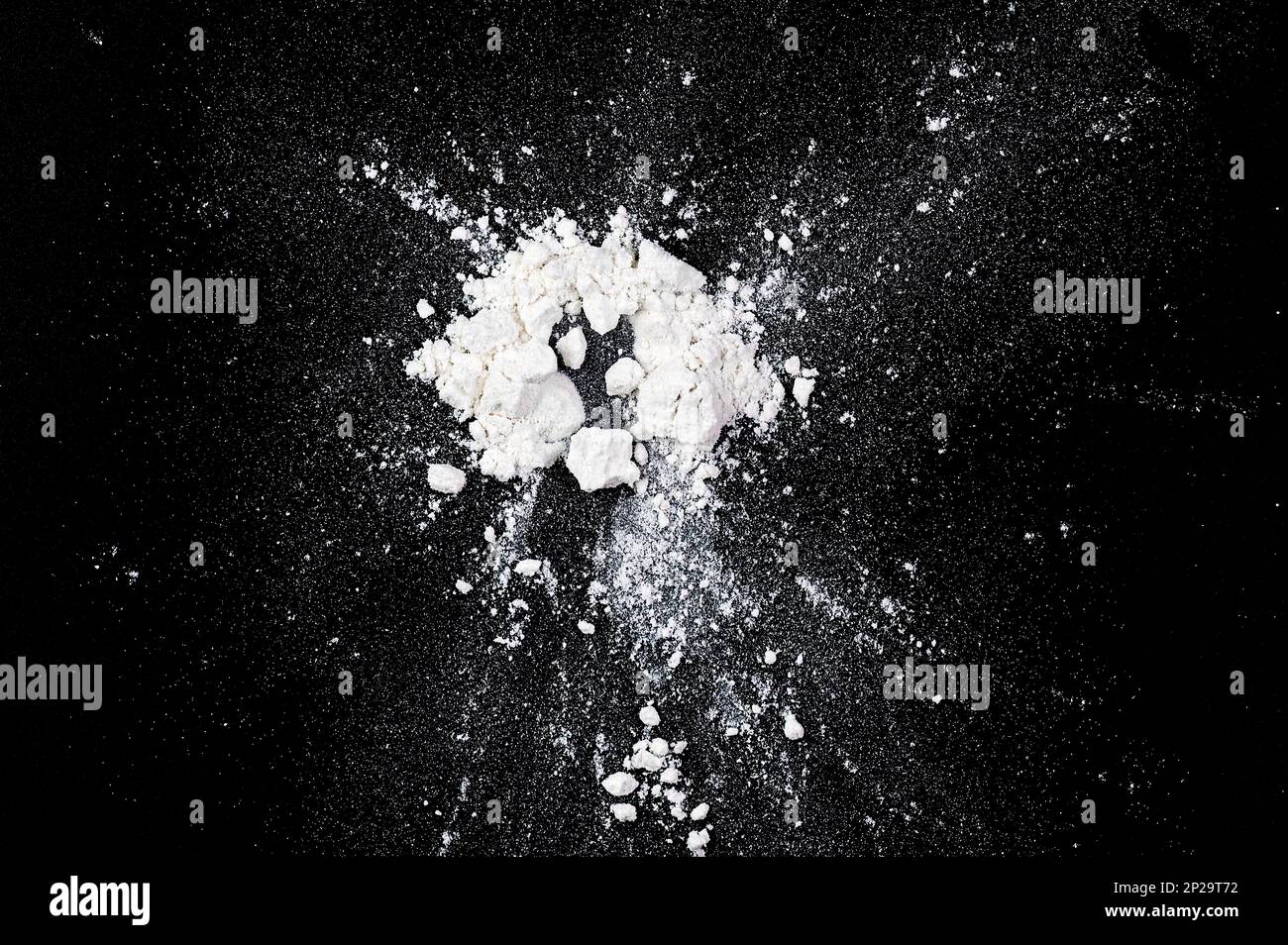 Spritzer von natürlichem weißem Mehl, Pulver auf schwarzem Brett, Draufsicht als Textur oder Hintergrund Stockfoto