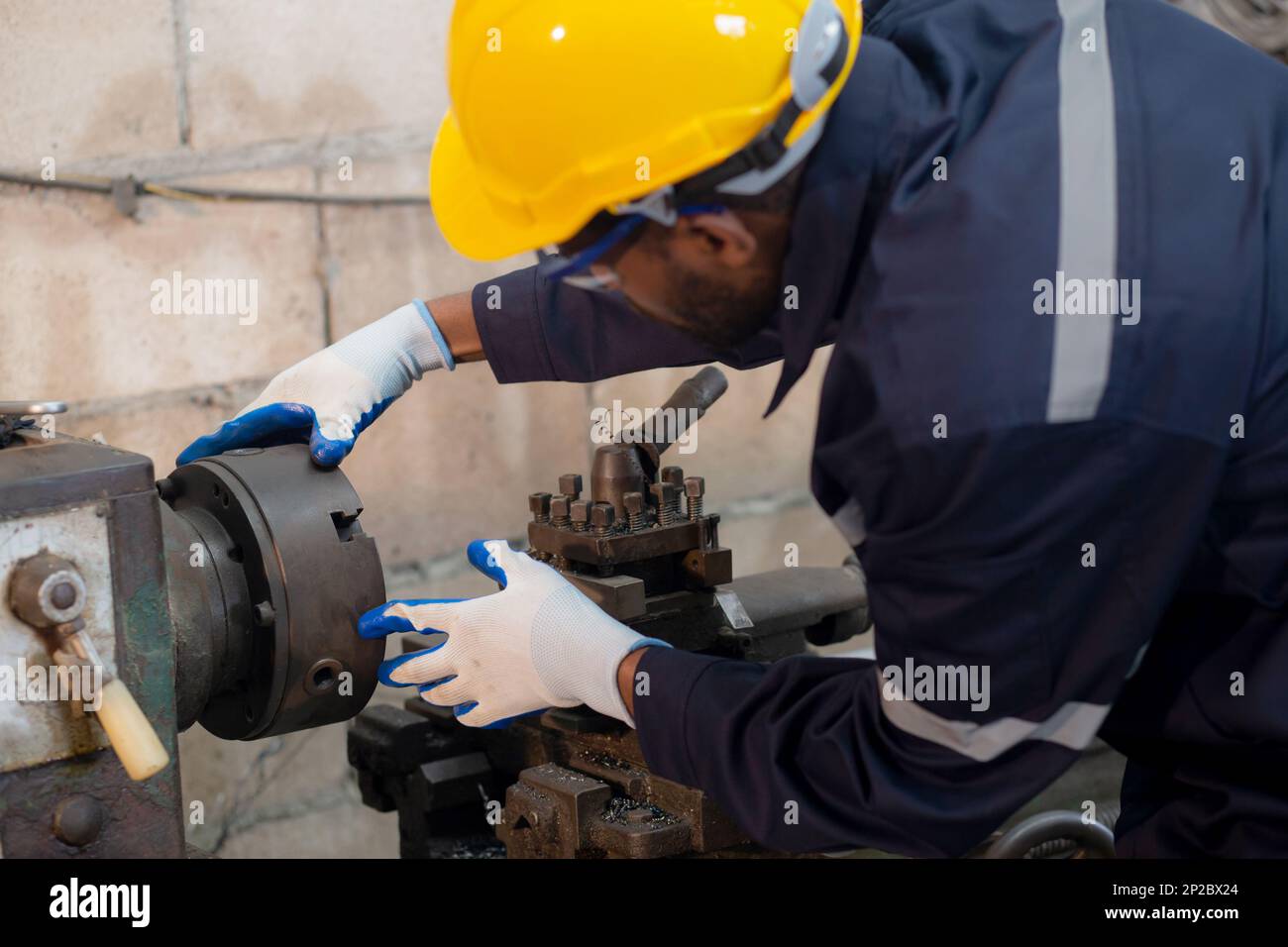 Junger schwarzer Ingenieur, der Maschinen mit Erfahrung in der Drehwerksfabrik, Arbeiter oder Techniker untersucht und wartet, Prüfwerkzeug für die Vorbereitung der arbeit mit wi Stockfoto