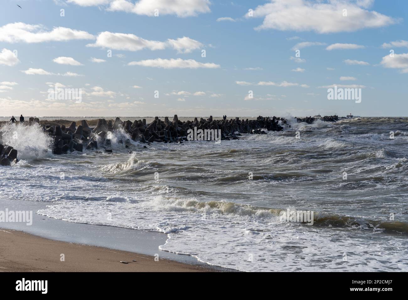 Wellen, die gegen das Wellenbrecherwasser stürzen, das aus Graubeton-Tetrapoden besteht. Liepaja, Lettland. Liepājas Ziemeļu mols Stockfoto