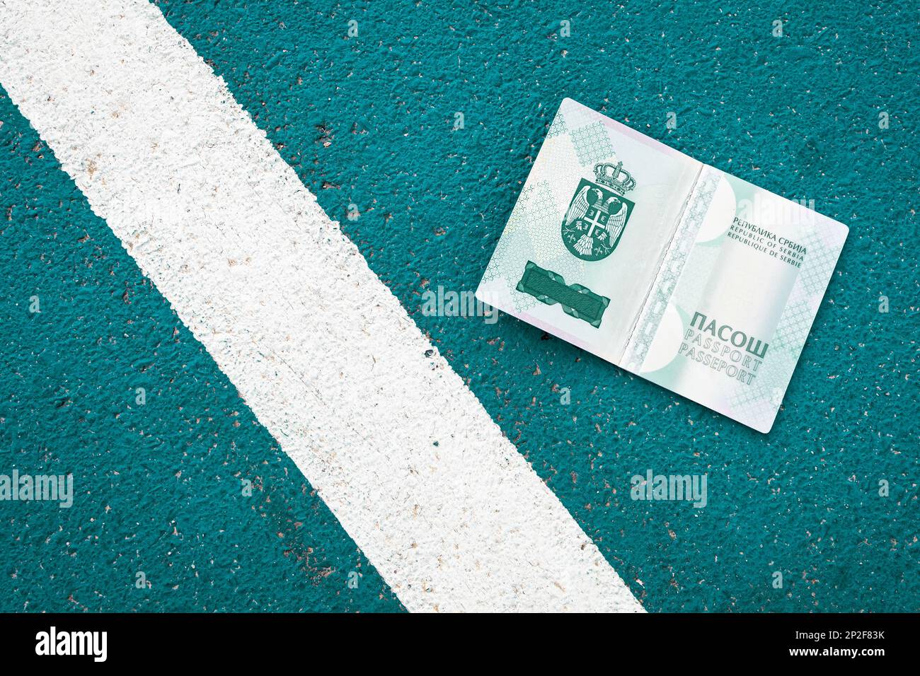 Offener serbischer Pass neben einer weißen Linie am Boden. Symbolisch, Rand Stockfoto