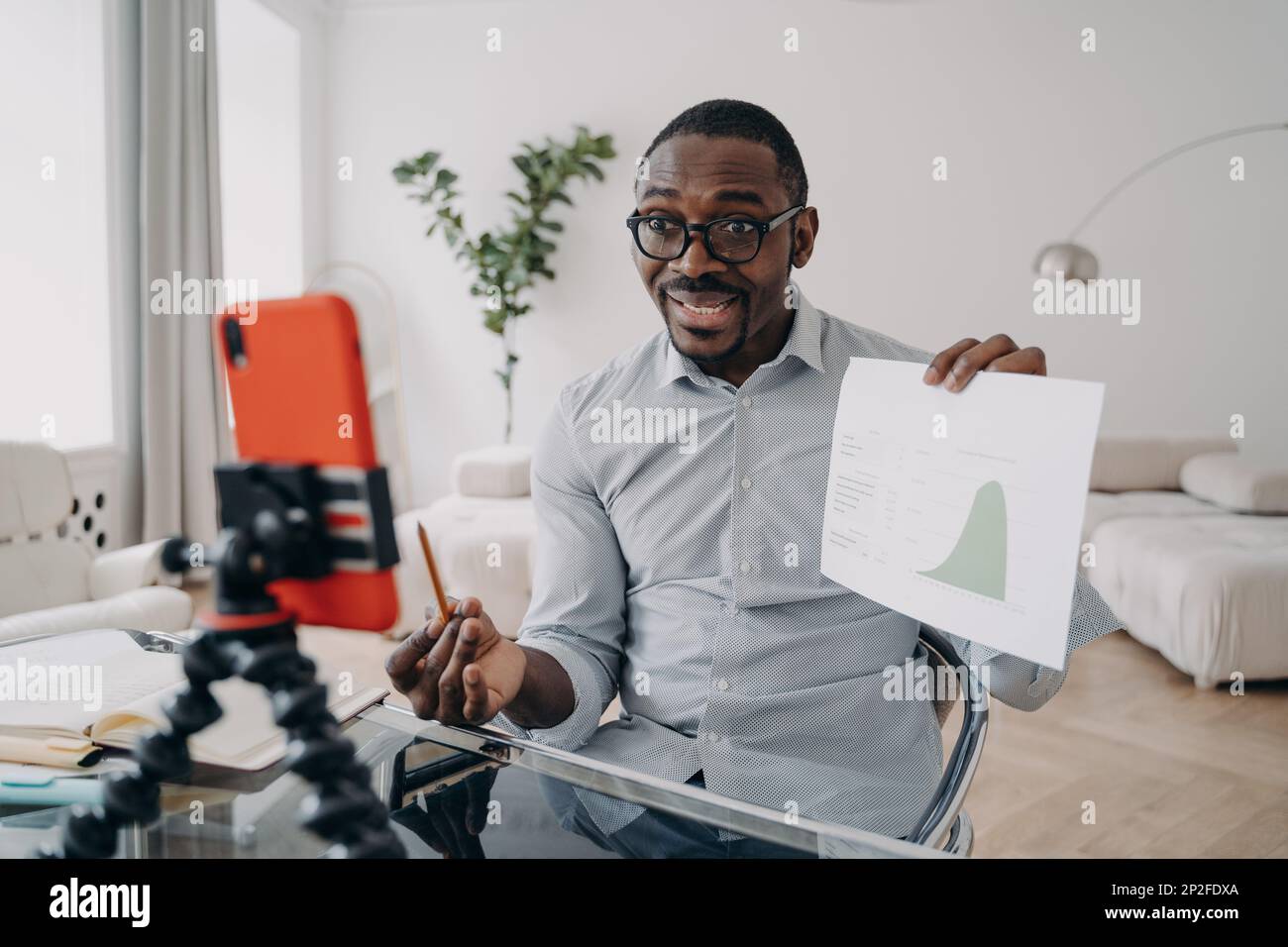Ein afroamerikanischer Mann-Ökonom zeigt eine Datengrafik, die einem Geschäftspartner per Videoanruf auf dem Smartphone präsentiert wird. Schwarzer männlicher Geschäftsmann-Coach diskutiert Stockfoto