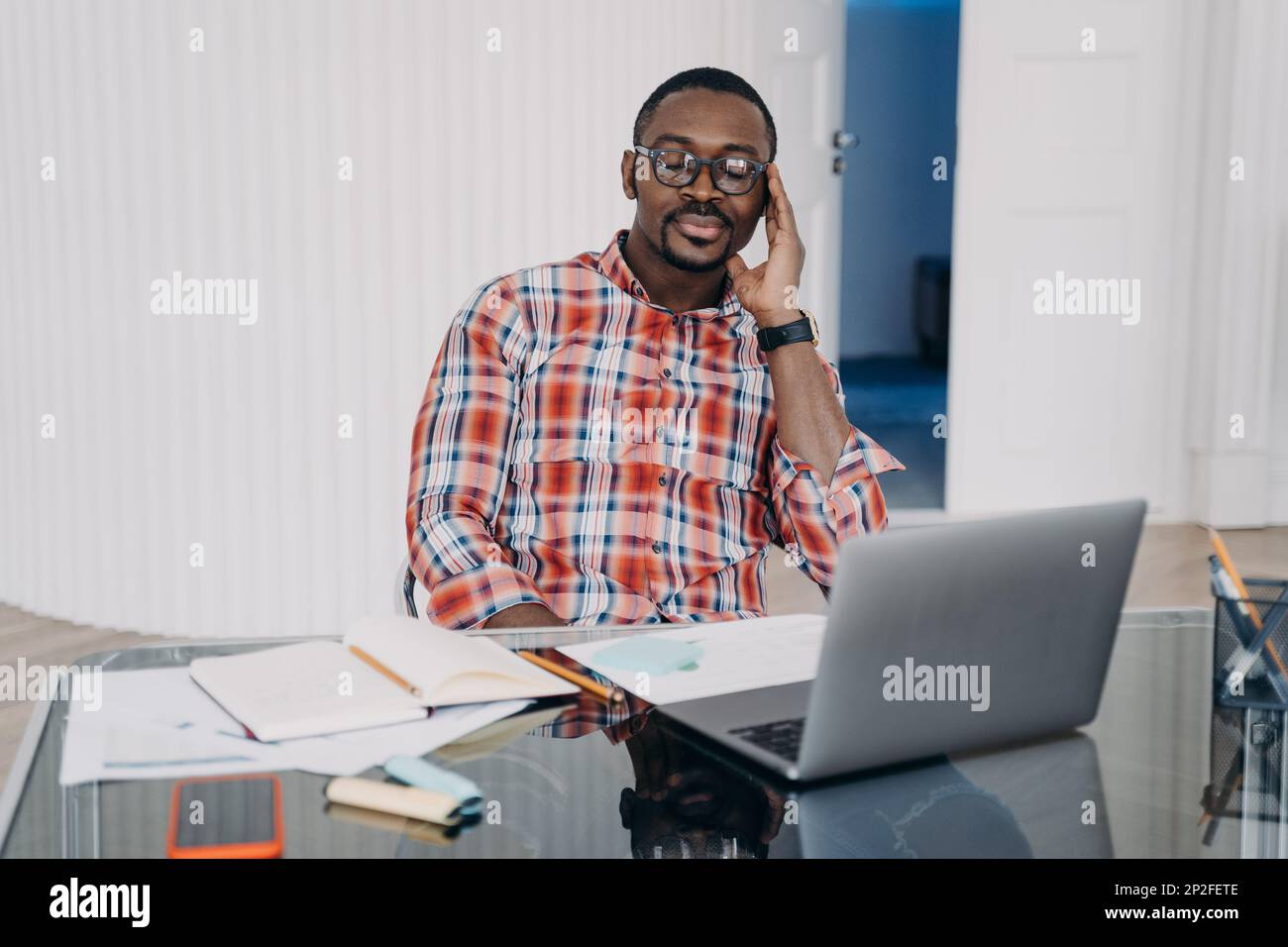 Müder afroamerikanischer Arbeiter mit geschlossenen Augen halten Kopf mit Hand entspannen, machen Sie eine Pause am Arbeitsplatz. Ein pensiver Schwarzer am Laptop sammelt Gedanken Stockfoto