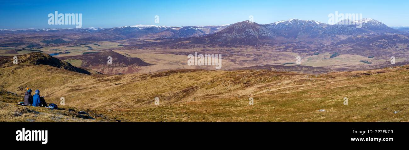 Zwei Wanderinnen, die sich auf dem Gipfel von Ben Vorlich in der Nähe von Pitlochry, Schottland, entspannen und die weitläufige Aussicht genießen Stockfoto