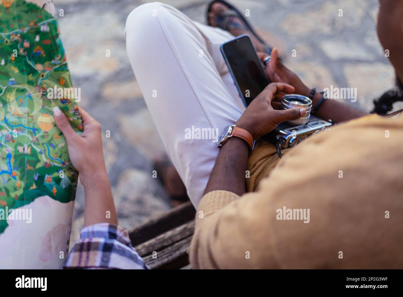 Ein Mann sitzt während einer Pause am Telefon. Seine Freundin sucht auf der Karte nach einem nächsten Reiseziel Stockfoto