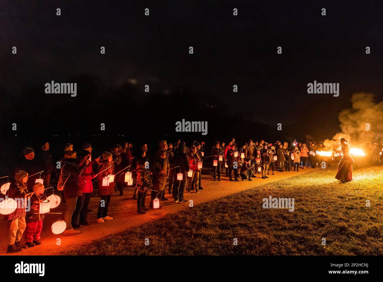 Leknica, Polen. 04. März 2023. Besucher stehen auf der polnischen Seite des Pückler Parks, wo eine Feuertänzerin eine Show veranstaltet. Auf dem Winter Light Festival, nach zwei Jahren Pause, Mehr als 1.000 Besucher wanderten von fünf verschiedenen Orten im Park, von Bad Muskau in Deutschland und ··knica in Polen im Licht ihrer Laternen, vorbei an bunt beleuchteten Gebäuden und Baumgruppen zur festlich beleuchteten Neuen Burg. Auf dem Burggarten konnten sich die Wanderer stärken und Live-Swing-Musik hören und anschauen. Kredit: Frank Hammerschmidt/dpa/Alamy Live News Stockfoto
