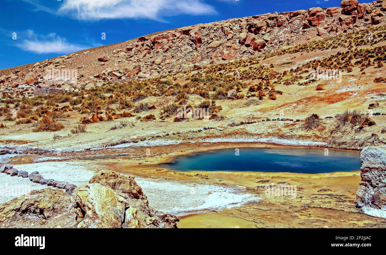 Wunderschöne farbenfrohe Vulkanlandschaft, geothermisches Tal mit natürlichem dunkelblauem heißen Pool, trockener Wüstenberg - El Tatio Geysire Field, Atacama d Stockfoto