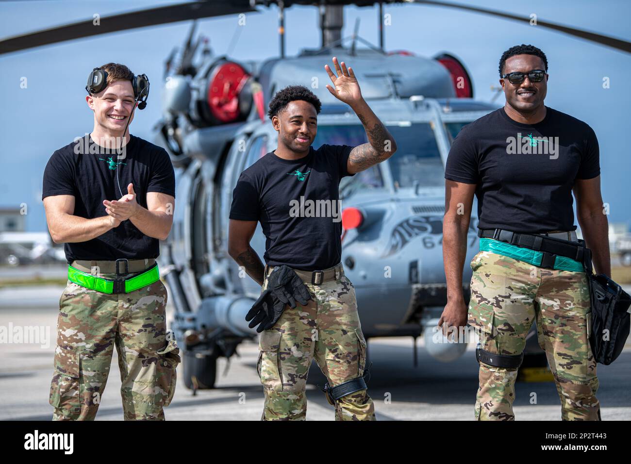 Senior Airman Noah Kohl, Left, Senior Airman Marcus Thomas, Center, und Staff Sgt. Matthew Banks, 33. Helicopter Maintenance Unit Weapons Specialists, lächeln während ihrer Vorstellung vor dem Publikum von Shogun Showdown, einem Waffenladerwettbewerb auf dem Luftwaffenstützpunkt Kadena, Japan, am 3. Februar 2023. Anstatt Sprengkörper in ihre Flugzeuge zu laden, hat die 33.-HMU-Ladetruppe zwei GAU-18-Maschinengewehre auf einen HH-60G-Pavehawk geladen, der der 33. Rettungsschwadron zugeteilt war. Stockfoto
