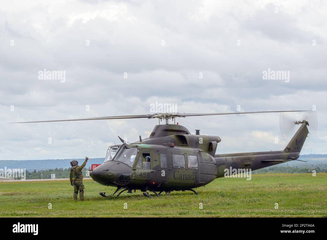 Moncton, NB, Kanada - 23. August 2014: Ein Soldat erteilt einem CH-146 Griffon Helikopter eine Daumen-hoch-Freigabe zum Start. Der Himmel ist bewölkt. Stockfoto