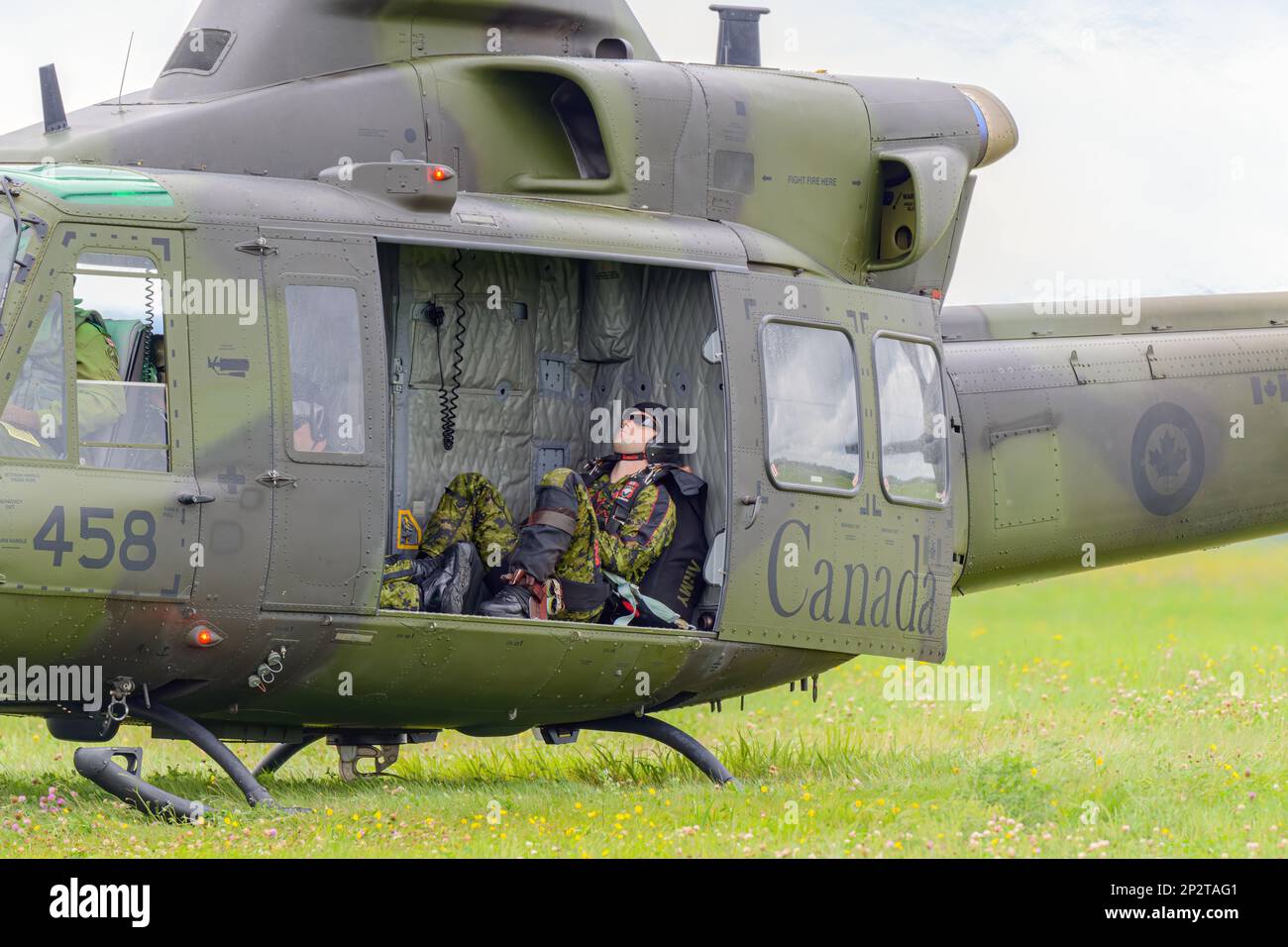 Moncton, NB, Kanada - 23. August 2014: Soldat macht ein Nickerchen in einem Griffon-Hubschrauber. Der Hubschrauber ist im Gras und die Seitentür ist offen. Stockfoto