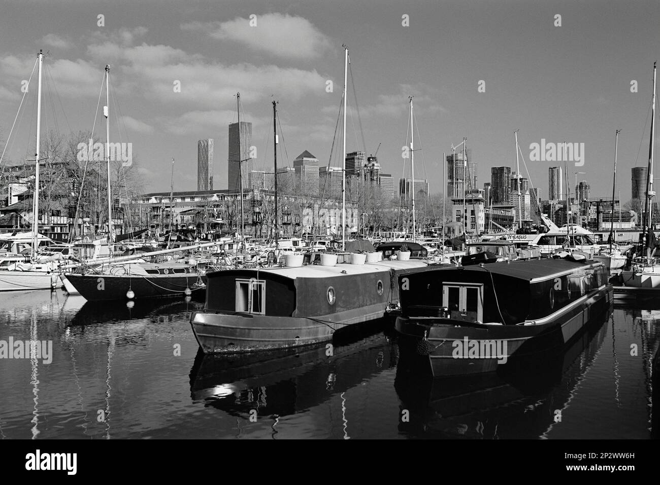 Hausboote und Yachten in South Dock, Rotherhithe, London Docklands, Großbritannien, mit Canary Wharf im Hintergrund Stockfoto