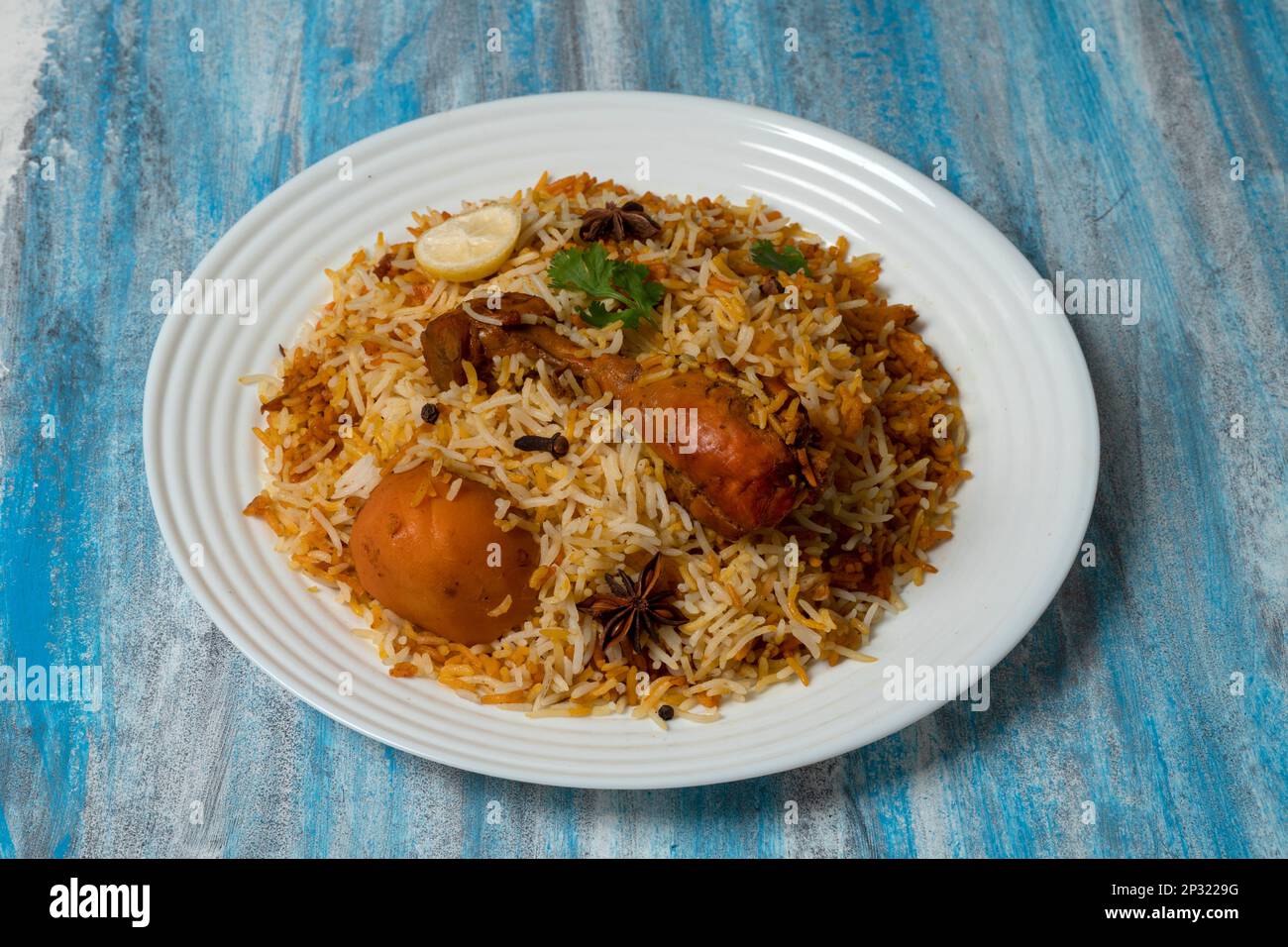 Chicken Biryani, beliebte pakistanische indische Küche auf weißem Teller mit strukturiertem Hintergrund. Stockfoto