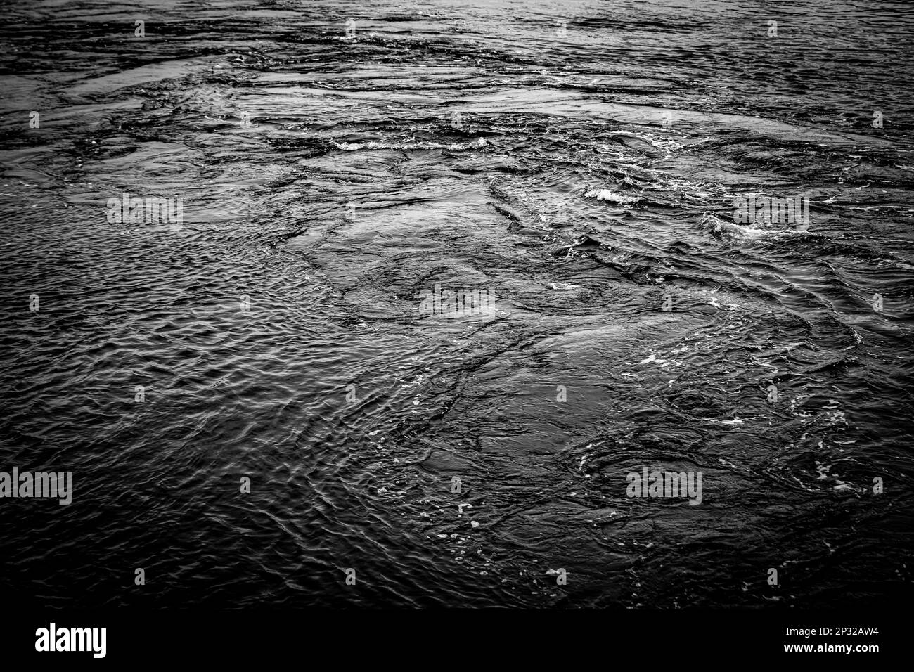 Wasser fließt in einem Fluss, der schwarz-weiß aussieht Stockfoto