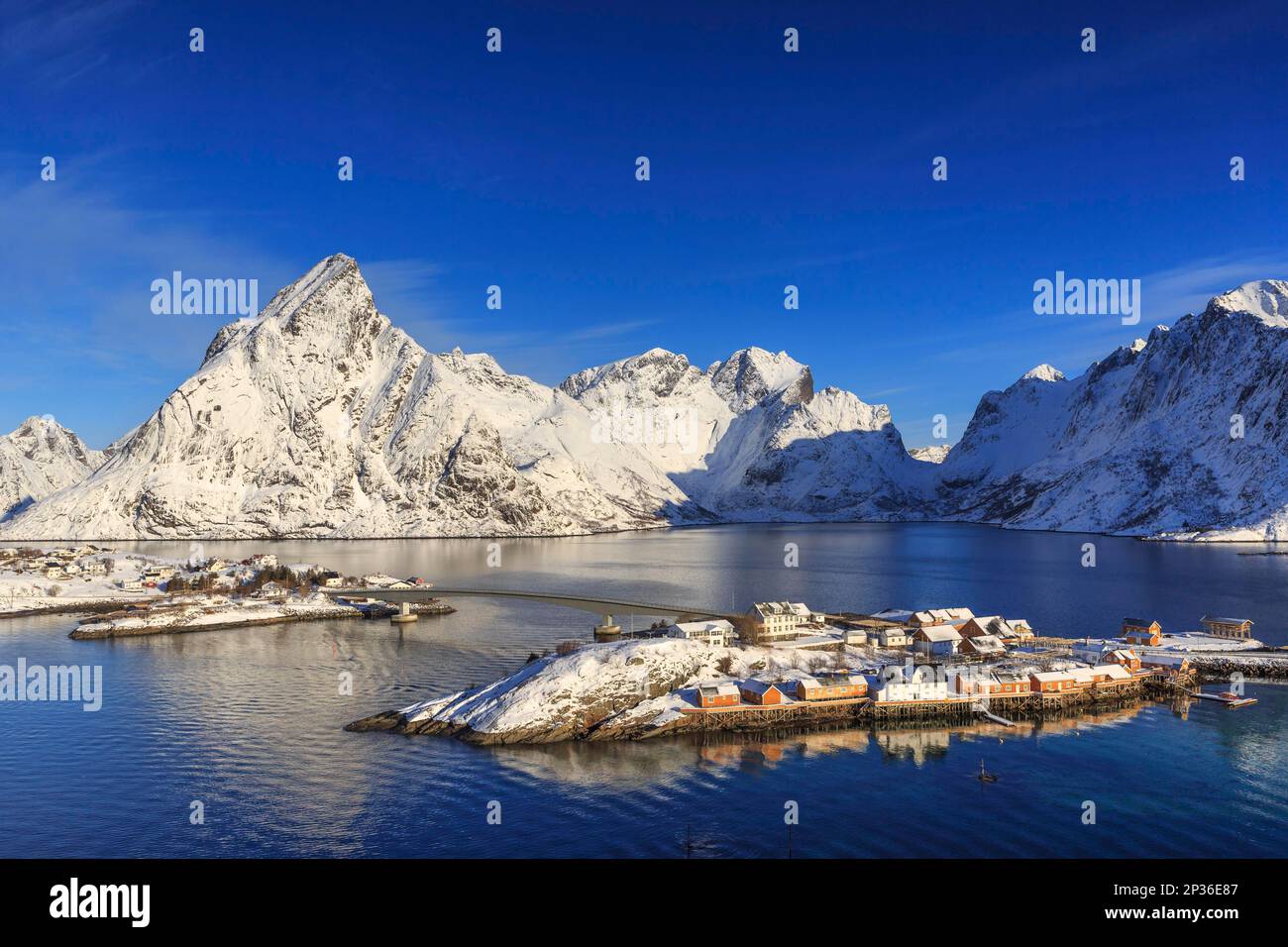 Gelber Flieger im Winter, Fischerhütten, schneebedeckte Berge dahinter, Sakrisoy, reine, Lofoten, Nordland, Norwegen Stockfoto