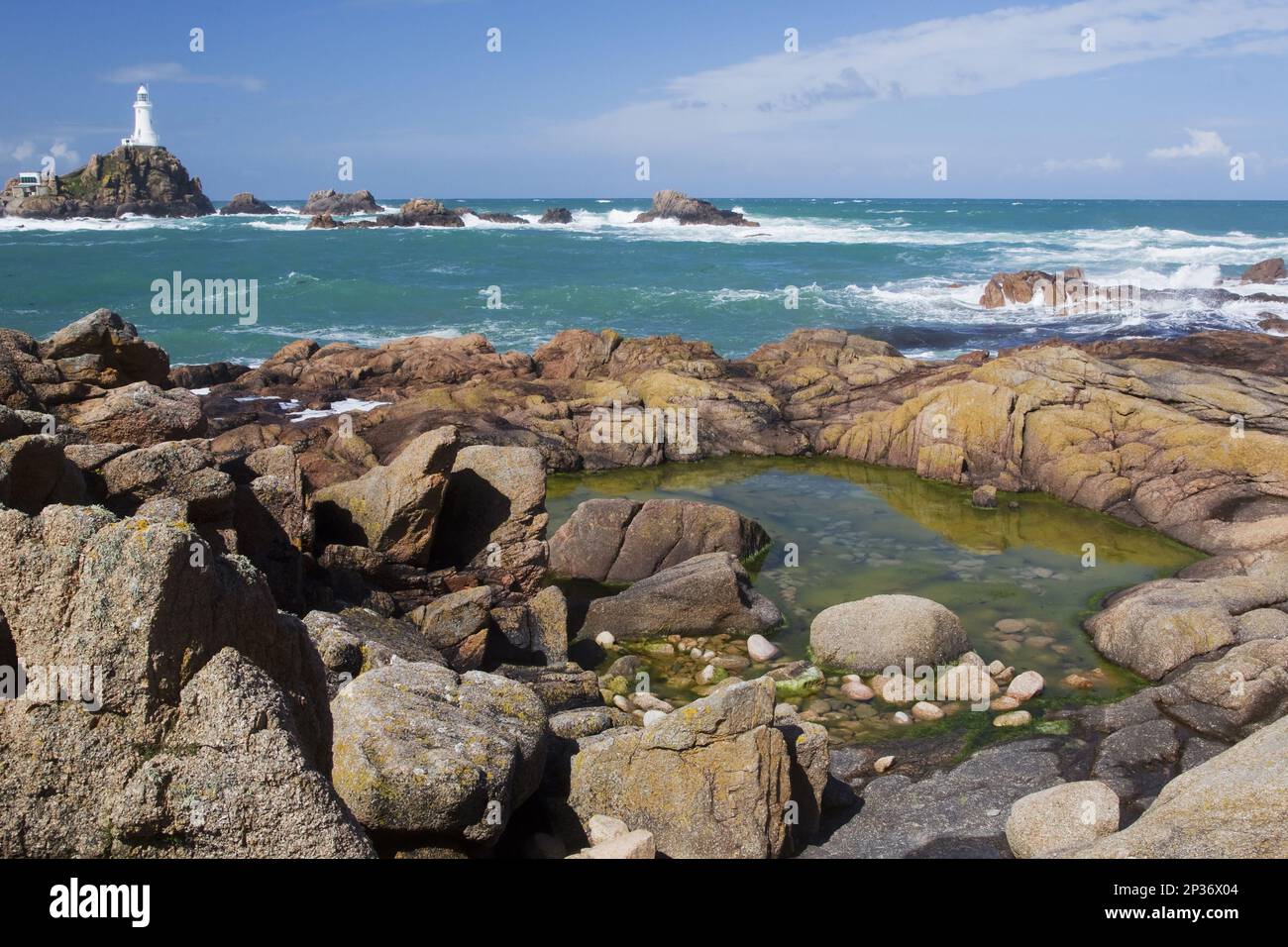 Felsenpool an der felsigen Küste bei Ebbe, mit Leuchtturm im Hintergrund, La Corbiere Lighthouse, La Corbiere, St. Brelade, Jersey, Kanalinseln Stockfoto