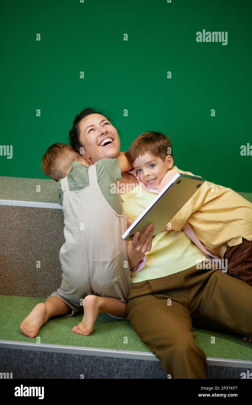 Kinder lenken die weiße Geschäftsfrau davon ab, online mit einem Laptop zu arbeiten. Kaukasische Familie glücklich zusammen. Hochwertiges Foto Stockfoto