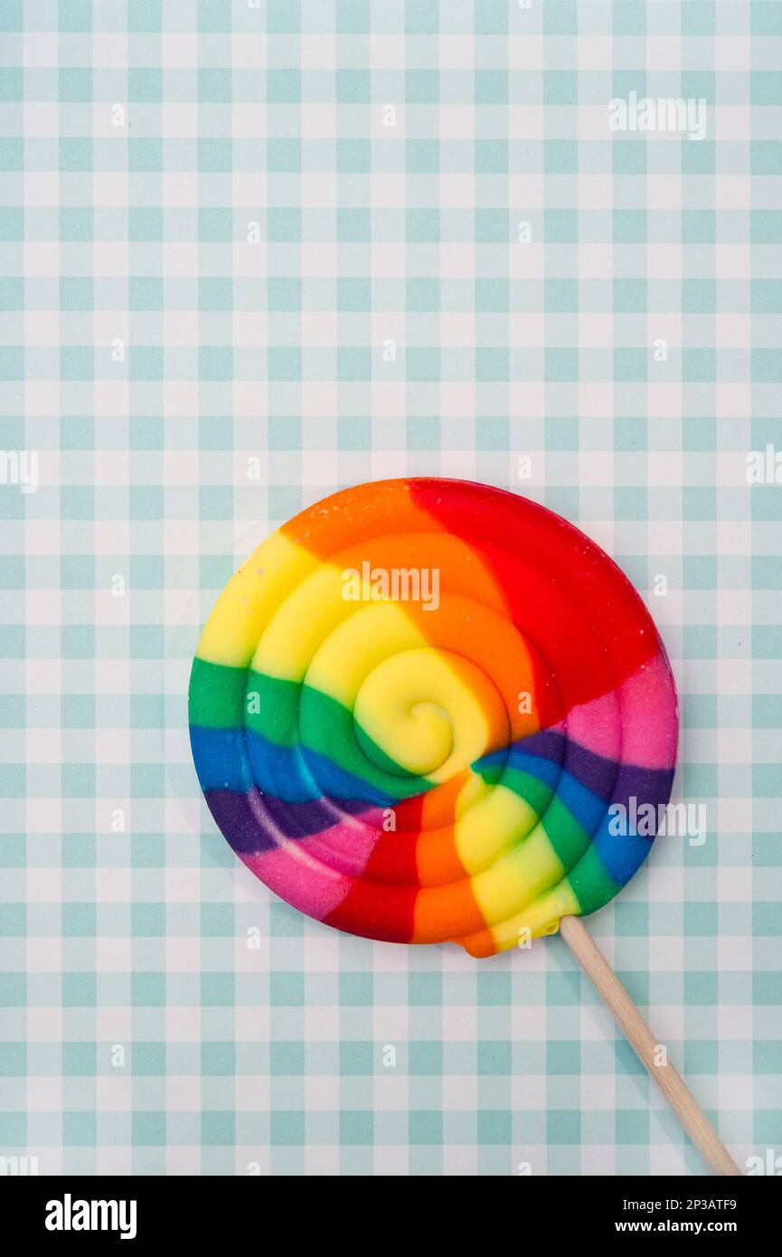 lollypop mit Regenbogenfarben gegen ein grünes Muster Stockfoto