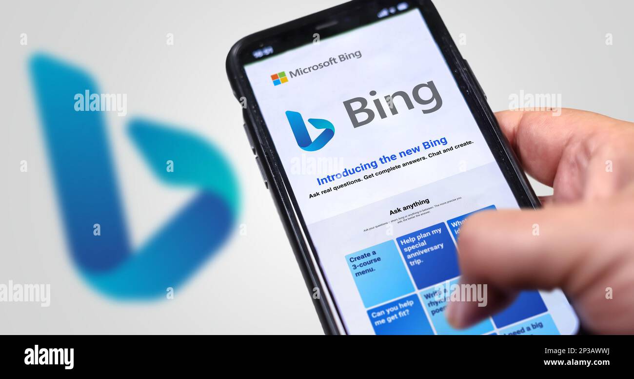 Redmond, USA, Februar 2023: Eine Hand, die ein Telefon hält und die Microsoft Bing-Website auf dem Bildschirm angezeigt wird. Weißer Hintergrund mit verschwommenem Bing-Logo. Bing ist eine Suche Stockfoto
