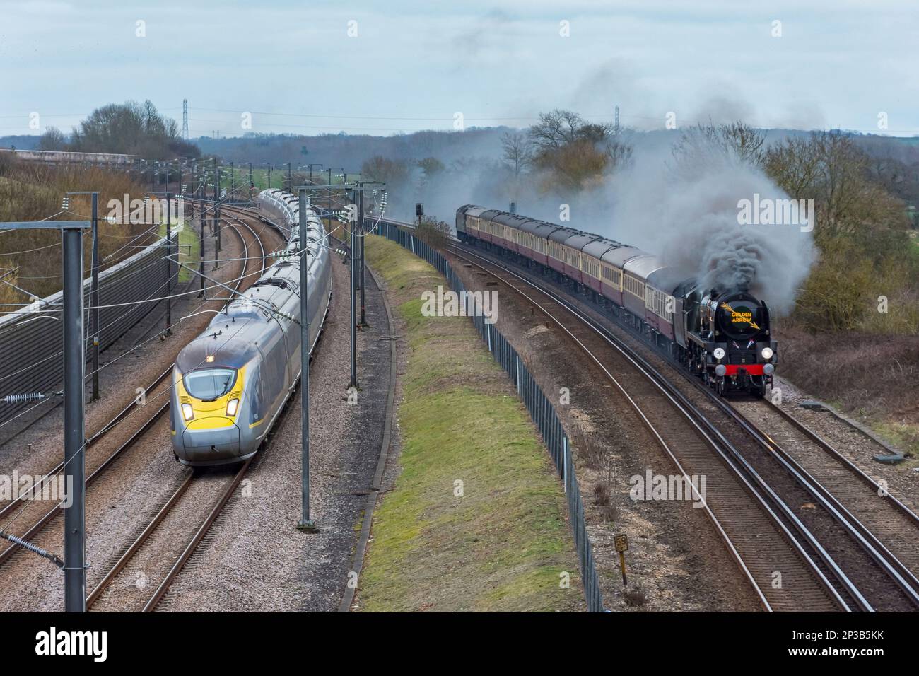 Die Dampfeisenbahn „34046 Braunton“, die den „Goldenen Pfeil“ durch Kent zieht, wird auf dem Weg nach London von ihrem modernen Äquivalent, einem Eurostar, passieren. Stockfoto