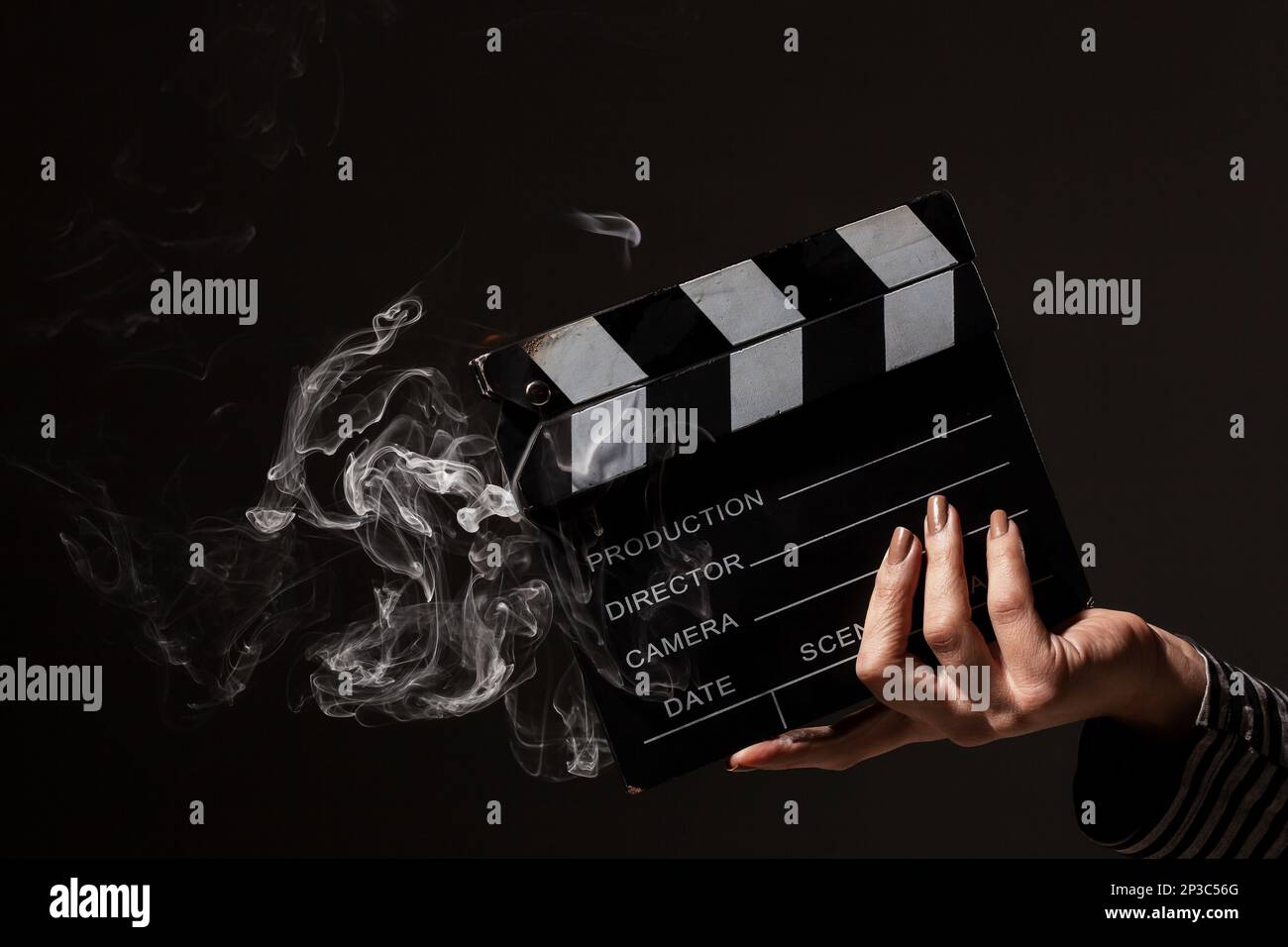 Weibliche Hand hält rauchenden Klapperboard. Rauch kommt aus heißen Film klatschen Board. Stockfoto