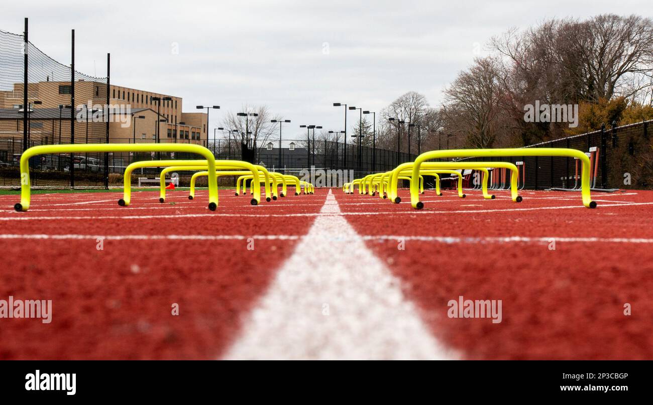 Blick vom Boden aus auf die gelben Mini-Hürden, die in Fahrspuren auf einer Rennstrecke für das Geschwindigkeitstraining auf der High School-Rennstrecke und im Feldtraining aufgestellt sind. Stockfoto