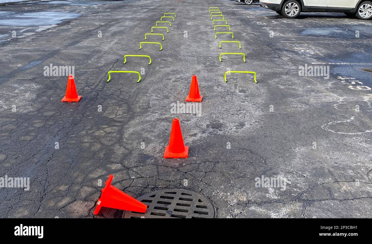 Kleine Yello-Hürden setzen dich in Abschleppreihen auf einen Parkplatz, über den ein High School Leichtathletikteam nach einem Schneesturm die Strecke überfahren kann. Stockfoto