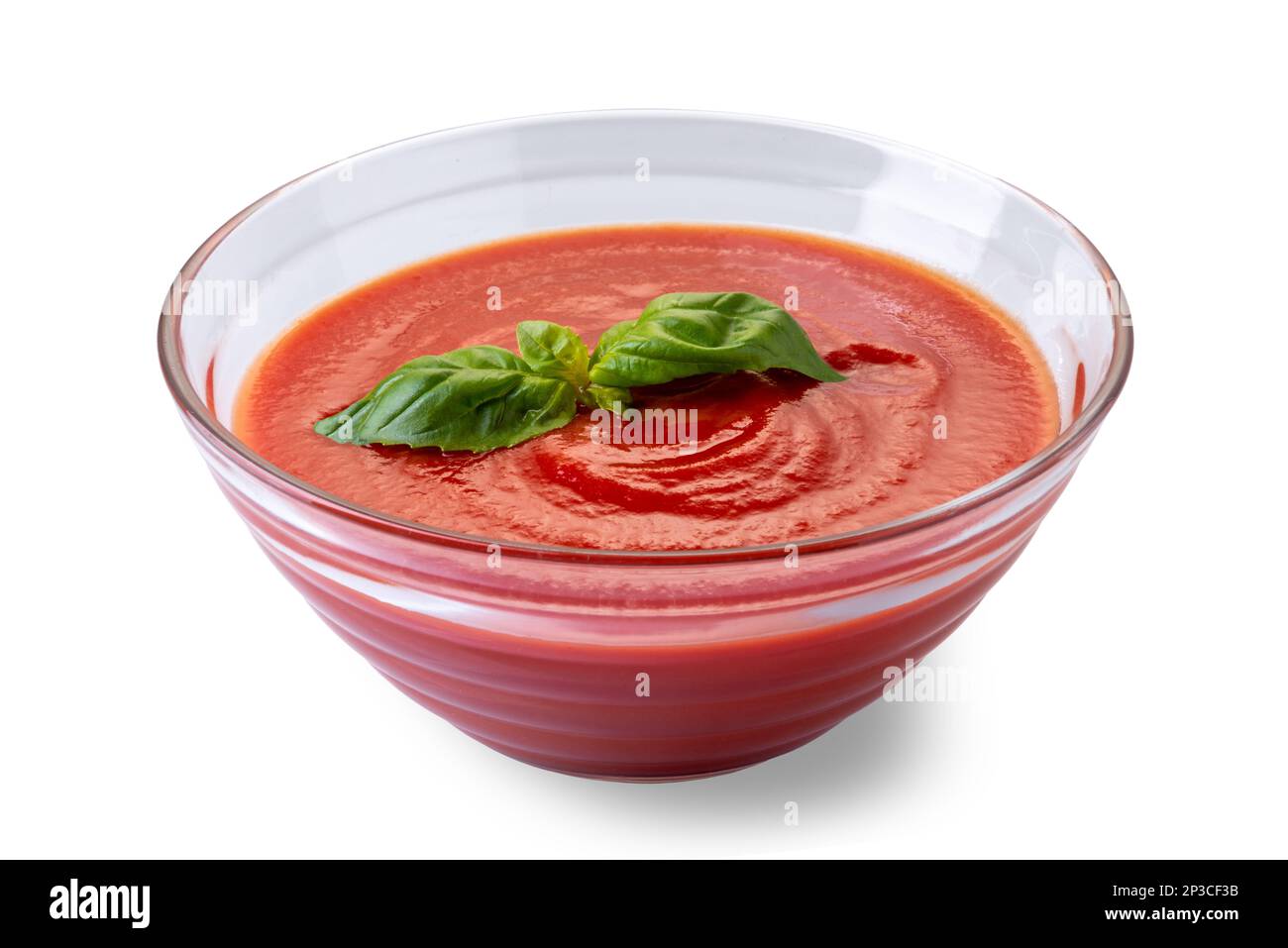 Glasbecher mit Tomatenpüree-Sauce mit Basilikumblättern, auf weiß isoliert, mit Schnittpfad Stockfoto