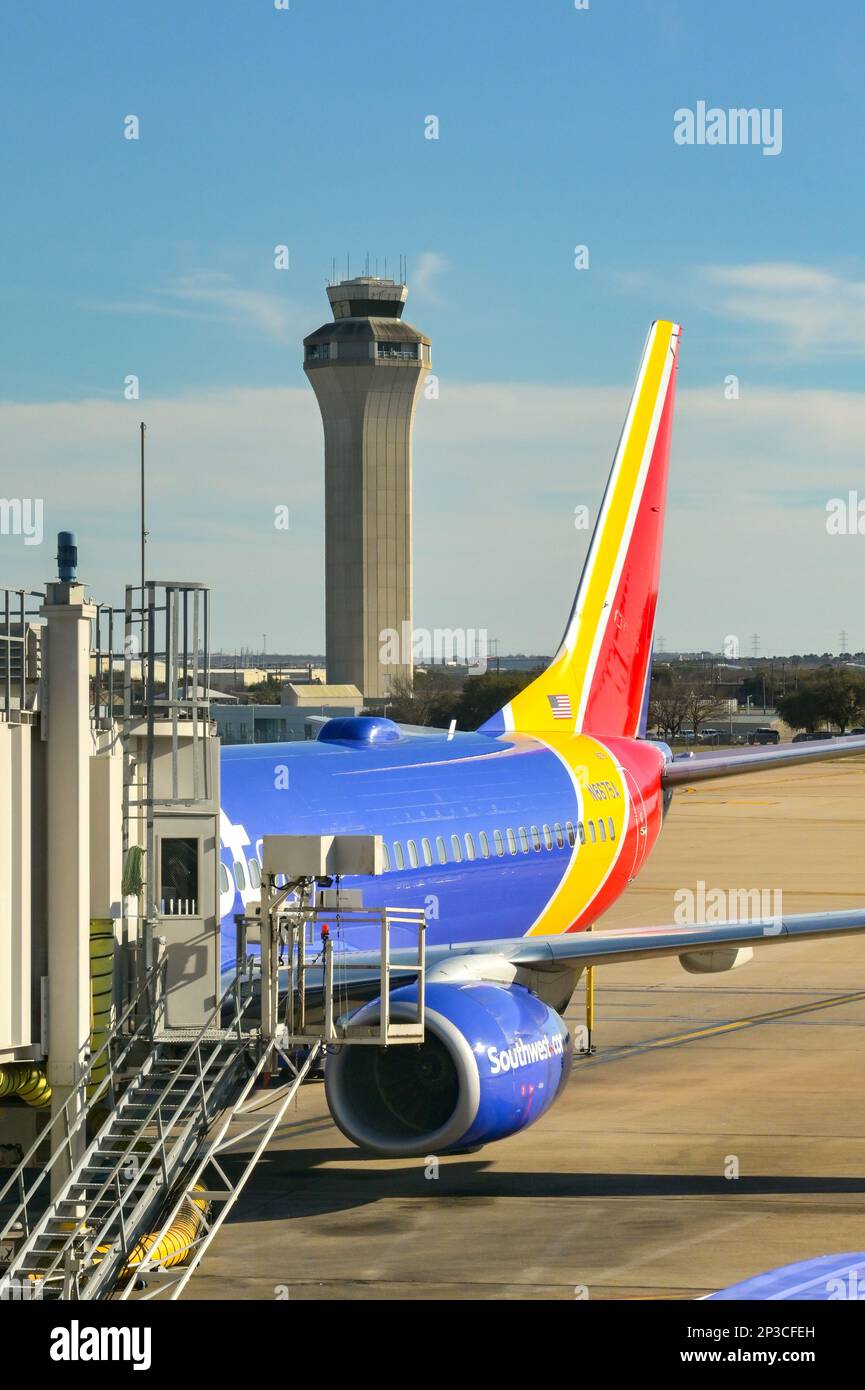 Austin, Texas - Februar 2023: Heckflosse eines Passagierflugzeugs der Boeing 737 von Southwest Airlines am Terminal mit dem Flugverkehrskontrollturm des Flughafens Stockfoto