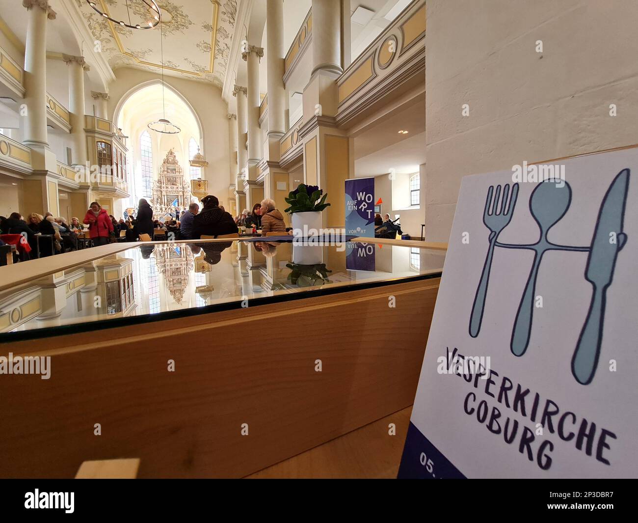 Coburg, Deutschland. 05. März 2023. Ein Schild mit der Aufschrift „Vesperkirche Coburg“ steht an einer Wand an der Öffnung der Vesperkirche im Kirchenzimmer von St. Moriz. Die Vesperkirche bietet Mittagessen, kulturelle Veranstaltungen und andere Aktivitäten für zwei Wochen. Kredit: Pia Bayer/dpa/Alamy Live News Stockfoto